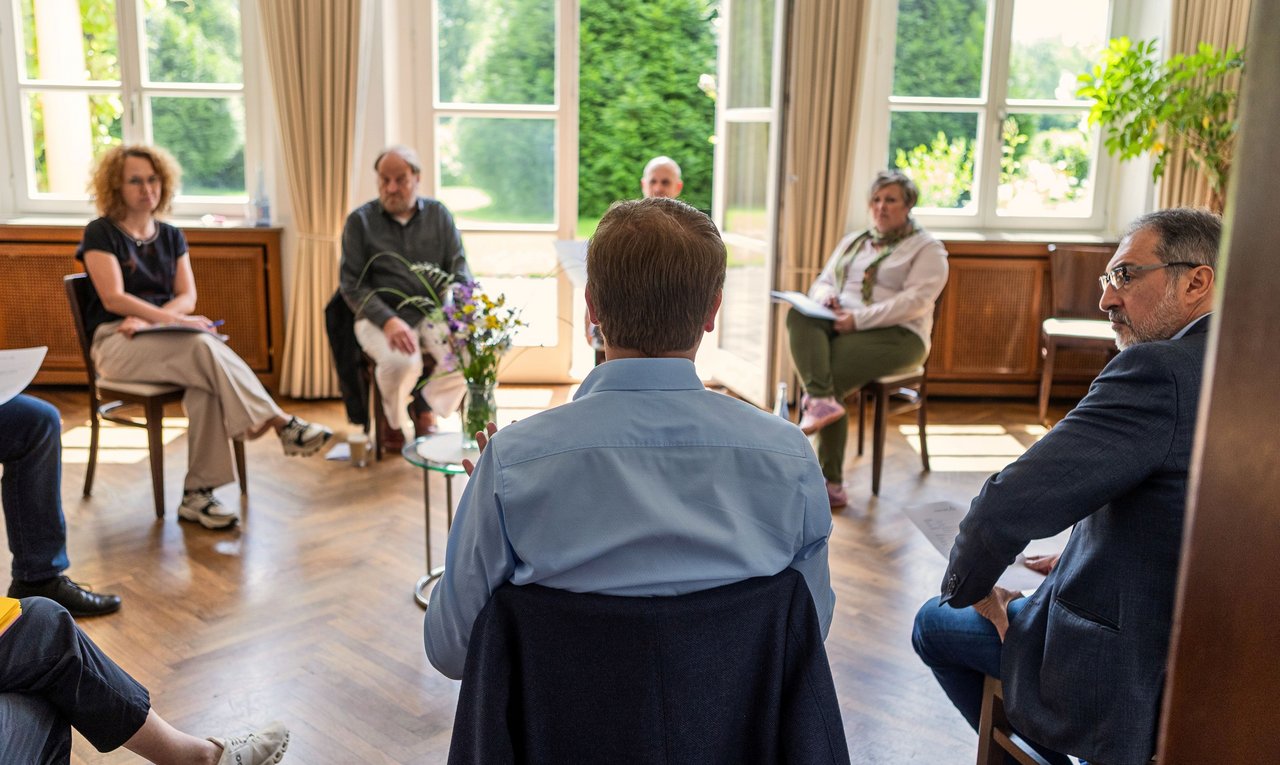 Eine Gruppe von Menschen sitzt in einem Stuhlkreis