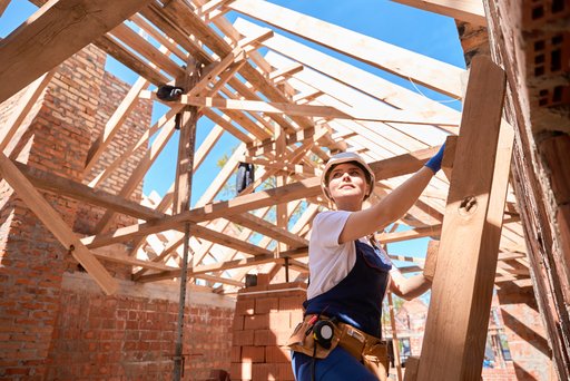 Das Bild zeigt eine Zimmermeisterin bei ihrer Arbeit auf einem Dachstuhl.