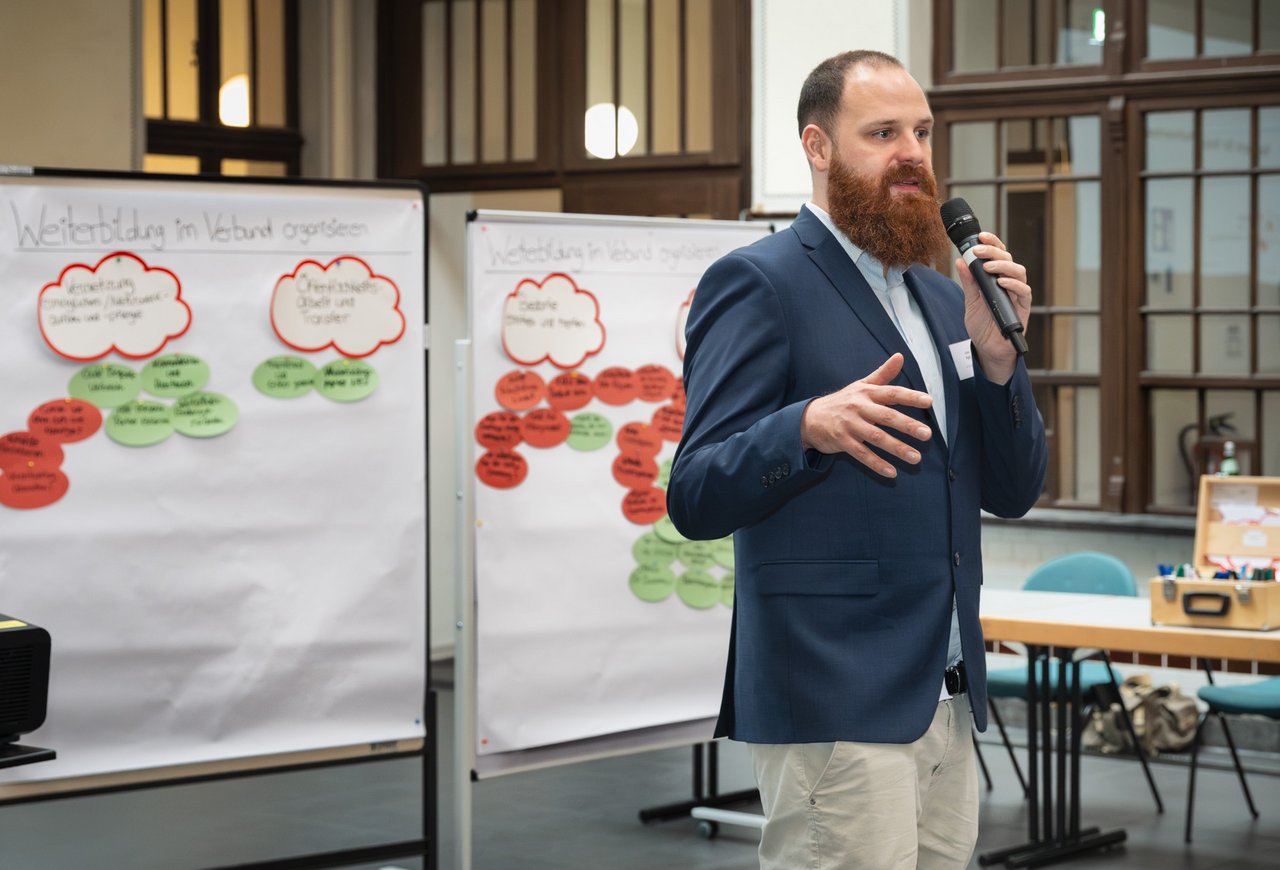 Das Foto zeigt Julian Agel vor Metaplanwänden im Fachforum, während er moderiert..