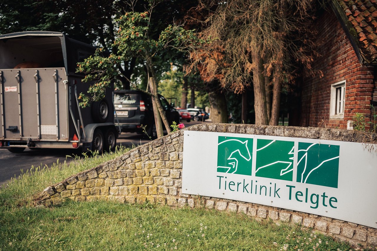 Eine Mauer vor einem Bauernhaus, auf der ein Schild der Tierklinik Telgte angebracht ist.