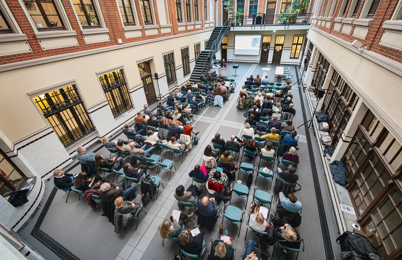 Das Foto zeigt die Lohnhalle mit den Teilnehmenden der Veranstlatung von oben.