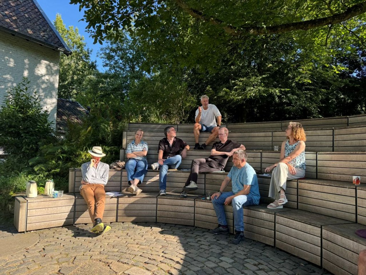 Personen sitzen entspannt auf Holzkisten, die treppenartig angeordnet sind. 
